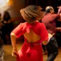 Dancing woman wearing a red dress with other dancers in the background